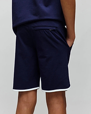 Kids Toby Short, navy relaxed fit French terry shorts featuring white piping on the hem and a subtle Psycho Bunny bunny skull logo tag on the back pocket, embodying refined streetwear.
