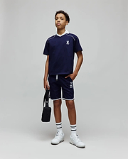 Navy blue polo with white collar and piping, featuring an embroidered bunny skull on the chest, and Kids Toby Short with white trim and a large Psycho Bunny text logo on the leg.