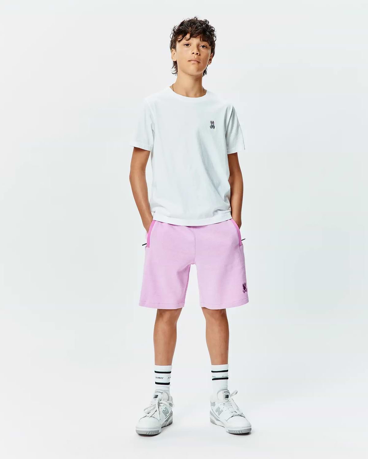 White jersey t-shirt with small embroidered Psycho Bunny logo on left chest, paired with Kids Keith Short 3 1/2 in light pink french terry, featuring a larger embroidered Psycho Bunny logo on the left leg and dark pink pocket trim.