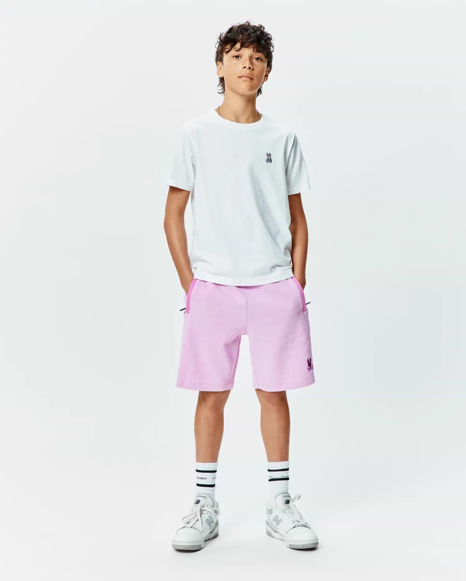 White jersey t-shirt with small embroidered Psycho Bunny logo on left chest, paired with Kids Keith Short 3 1/2 in light pink french terry, featuring a larger embroidered Psycho Bunny logo on the left leg and dark pink pocket trim.