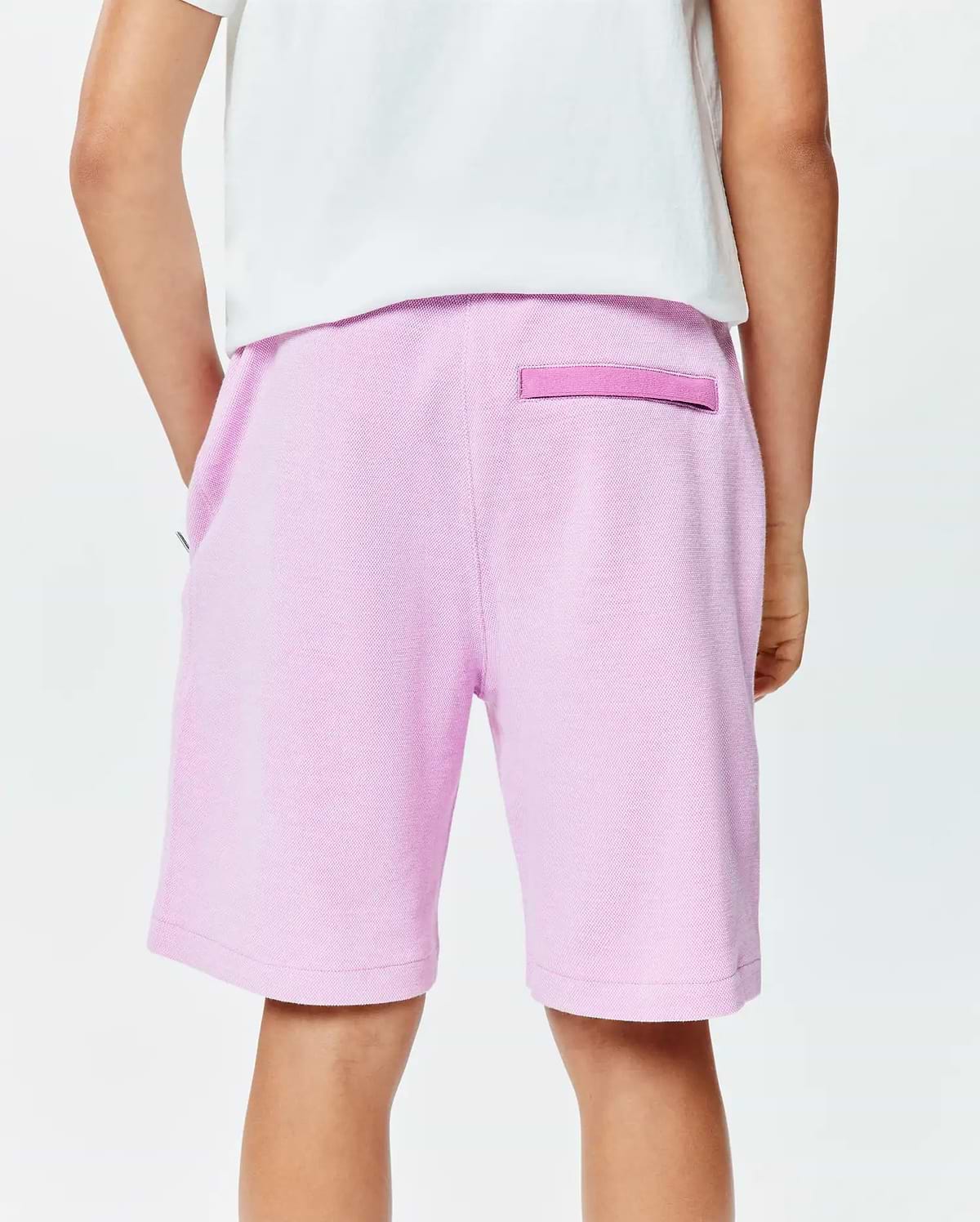 Kids Keith Short in light pink pique knit, featuring a relaxed fit, side pockets, and a darker pink signature Psycho Bunny back loop detail.