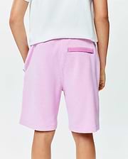 Kids Keith Short in light pink pique knit, featuring a relaxed fit, side pockets, and a darker pink signature Psycho Bunny back loop detail.