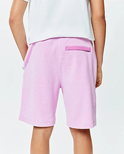 Kids Keith Short in light pink pique knit, featuring a relaxed fit, side pockets, and a darker pink signature Psycho Bunny back loop detail.