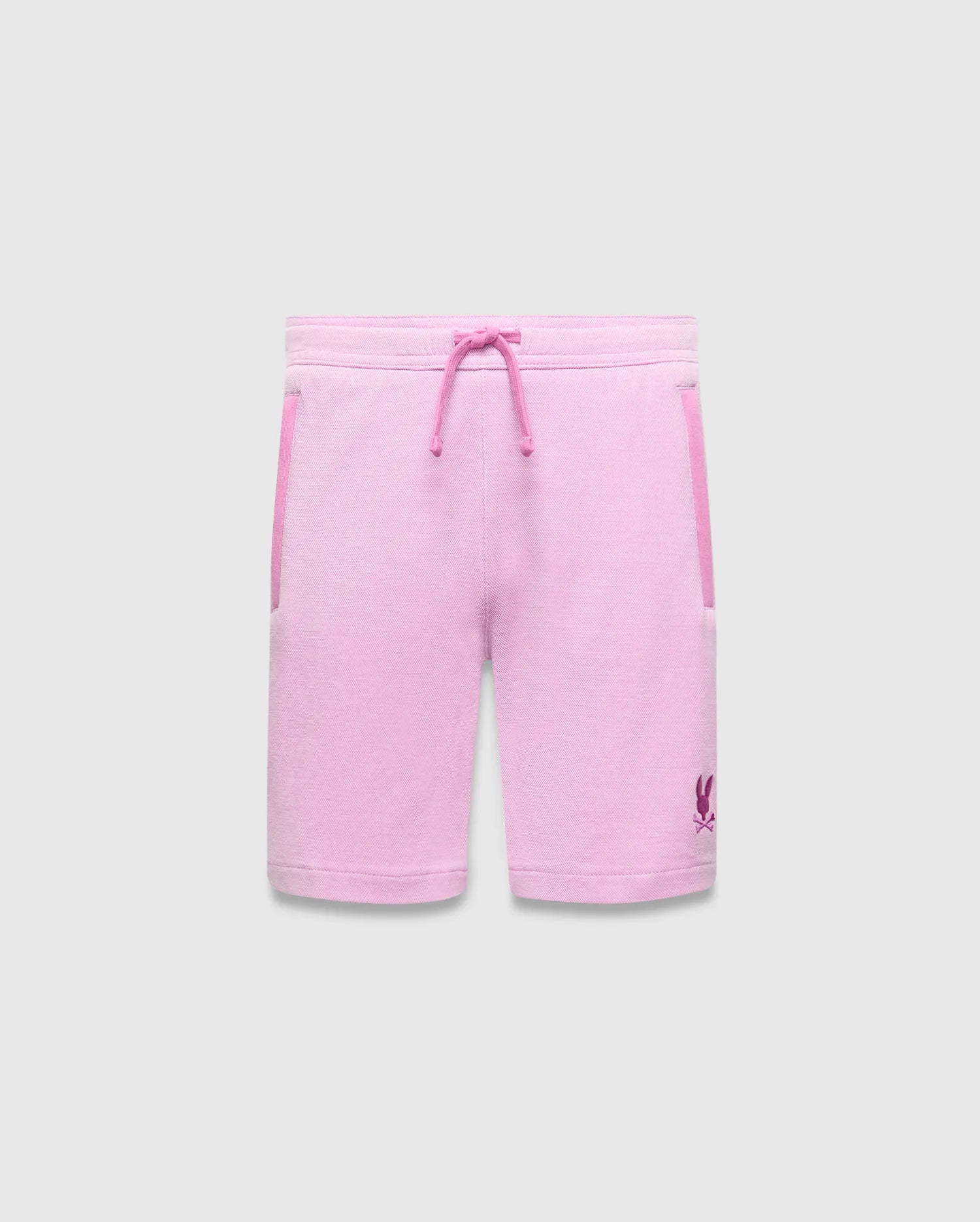 Kids Keith Short, a relaxed fit pink jersey short with magenta drawstring, side pocket trim, and a small embroidered Psycho Bunny skull logo on the lower left leg.