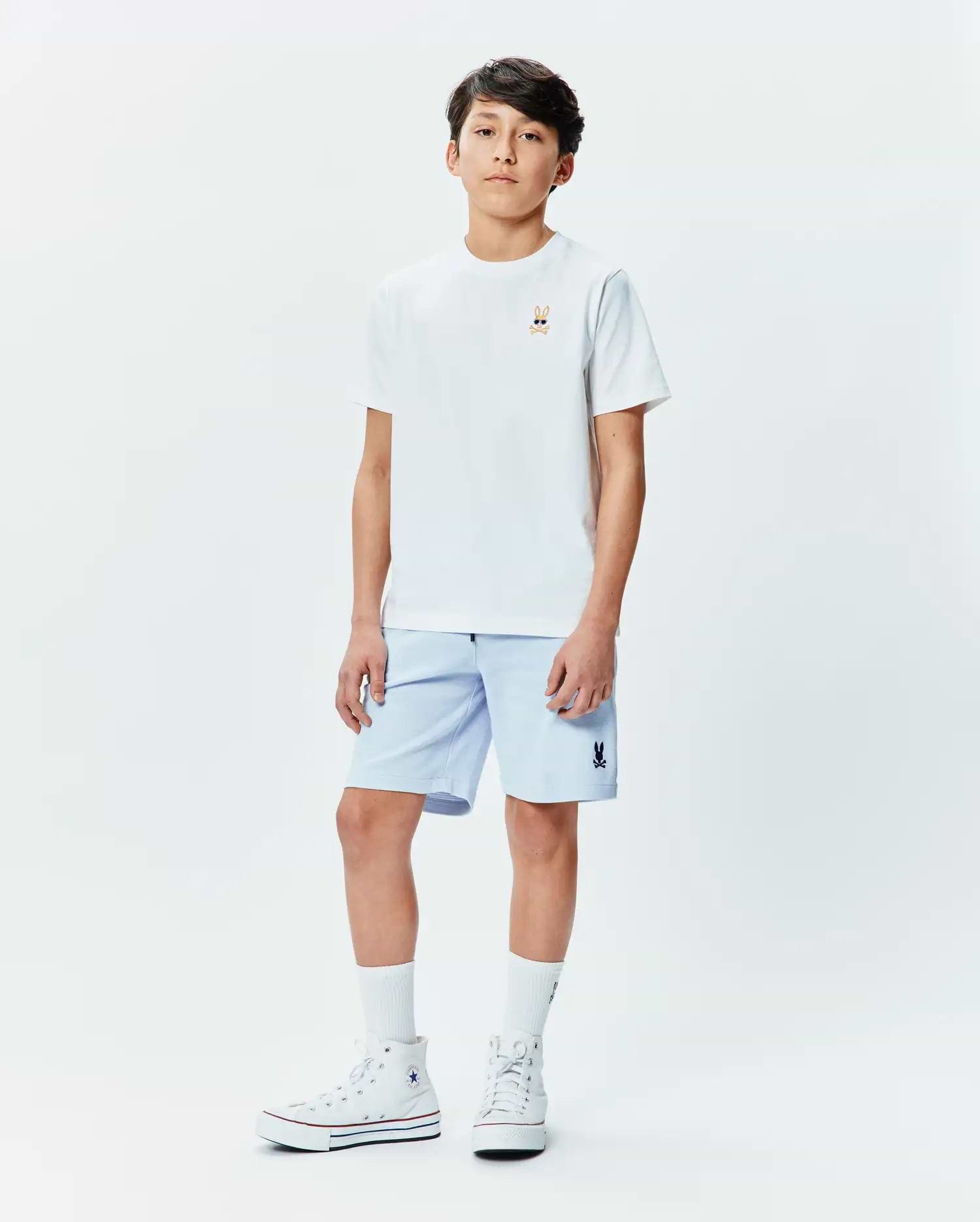 White classic fit jersey t-shirt with a small embroidered Psycho Bunny skull logo wearing sunglasses on the left chest, paired with light blue Kids Keith Short 3 1/2 with a small embroidered Psycho Bunny logo on the left leg. (4)