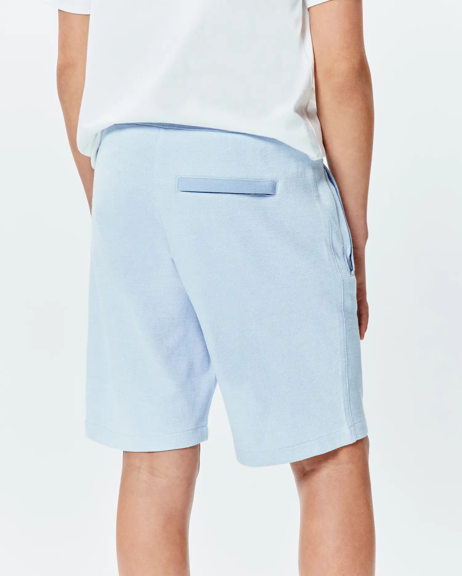 Light blue Kids Keith Short by Psycho Bunny, a relaxed pique knit with a back pocket featuring darker blue trim and side pockets. (3)