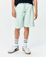 Kids Keith Short in light mint green pique knit, featuring a relaxed fit, drawstring waist with black tips, and a small embroidered Psycho Bunny skull logo on the lower left leg. (1)