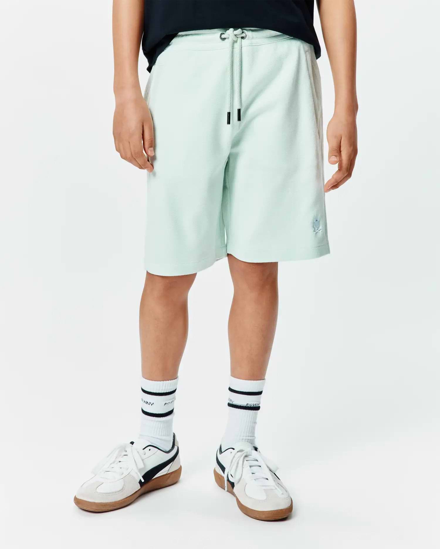Kids Keith Short in light mint green pique knit, featuring a relaxed fit, drawstring waist with black tips, and a small embroidered Psycho Bunny skull logo on the lower left leg. (1)
