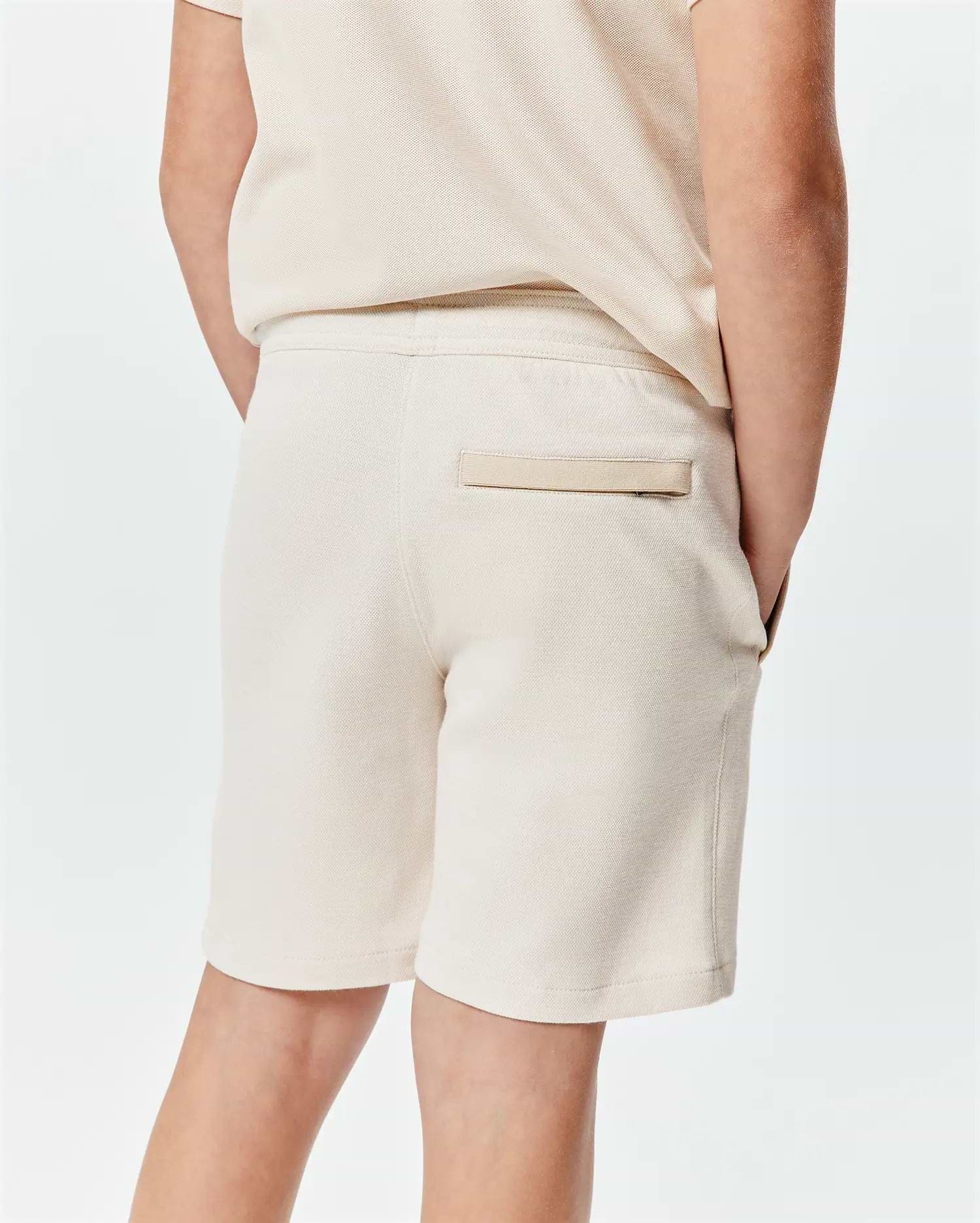 Kids Keith Short in a relaxed fit, cream pique knit fabric, featuring an elastic waistband and a subtle back welt pocket with a small tab detail.