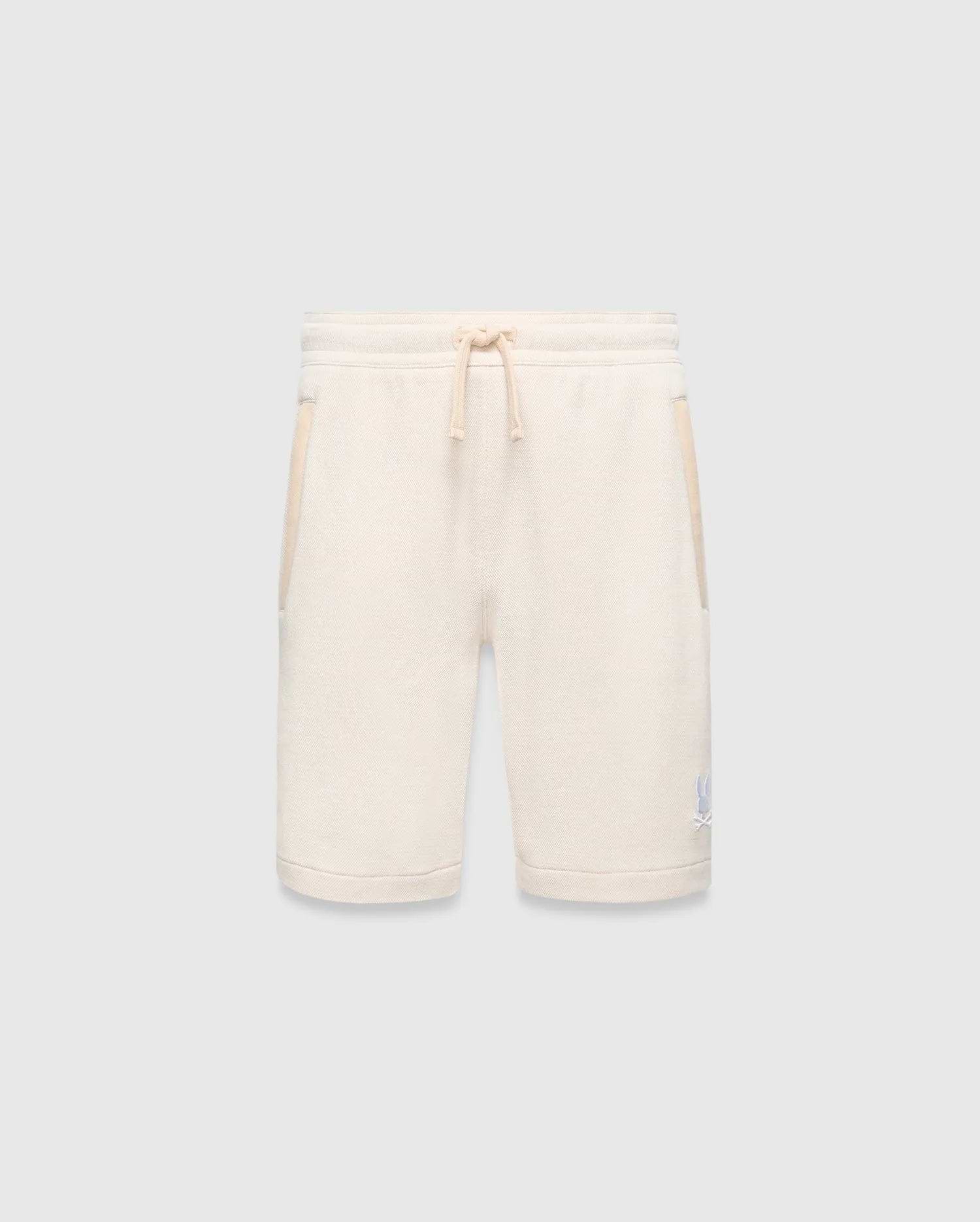 Kids Keith Short 3 1/2, a cream textured knit relaxed fit short with drawstring waist, light beige pocket trim, and a small embroidered light blue Psycho Bunny skull logo on the lower left leg.