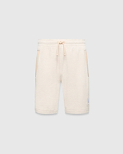 Kids Keith Short 3 1/2, a cream textured knit relaxed fit short with drawstring waist, light beige pocket trim, and a small embroidered light blue Psycho Bunny skull logo on the lower left leg.