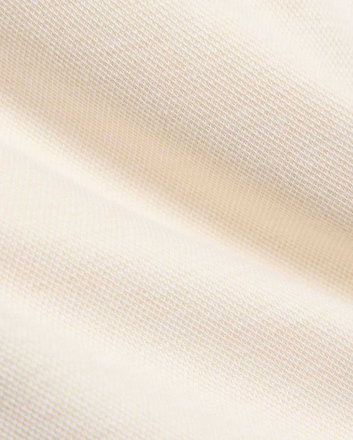 Creamy off-white pique knit fabric for the Kids Keith Short 3 1/2 7 3/4, featuring a finely textured, breathable weave with gentle folds, embodying the premium quality of Psycho Bunny apparel.