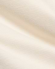 Creamy off-white pique knit fabric for the Kids Keith Short 3 1/2 7 3/4, featuring a finely textured, breathable weave with gentle folds, embodying the premium quality of Psycho Bunny apparel.