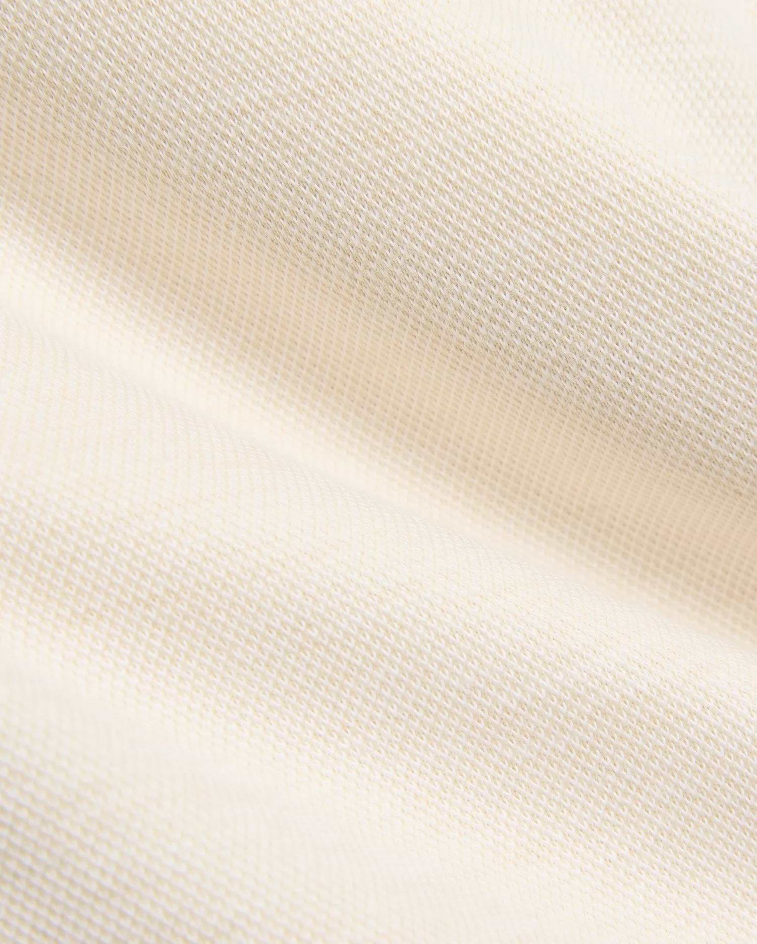 Creamy off-white pique knit fabric for the Kids Keith Short 3 1/2 7 3/4, featuring a finely textured, breathable weave with gentle folds, embodying the premium quality of Psycho Bunny apparel.