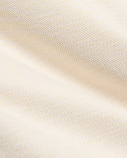 Creamy off-white pique knit fabric for the Kids Keith Short 3 1/2 7 3/4, featuring a finely textured, breathable weave with gentle folds, embodying the premium quality of Psycho Bunny apparel.