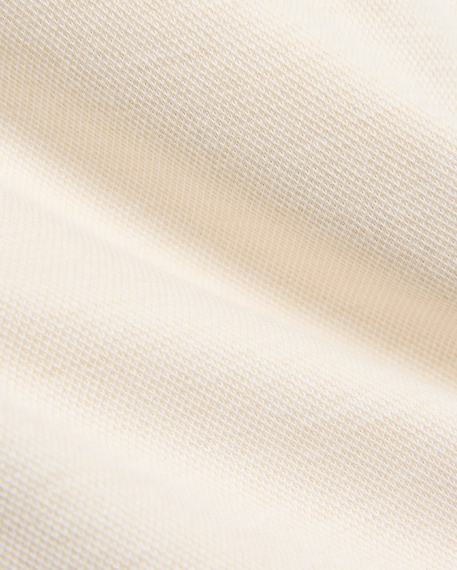 Creamy off-white pique knit fabric for the Kids Keith Short 3 1/2 7 3/4, featuring a finely textured, breathable weave with gentle folds, embodying the premium quality of Psycho Bunny apparel.