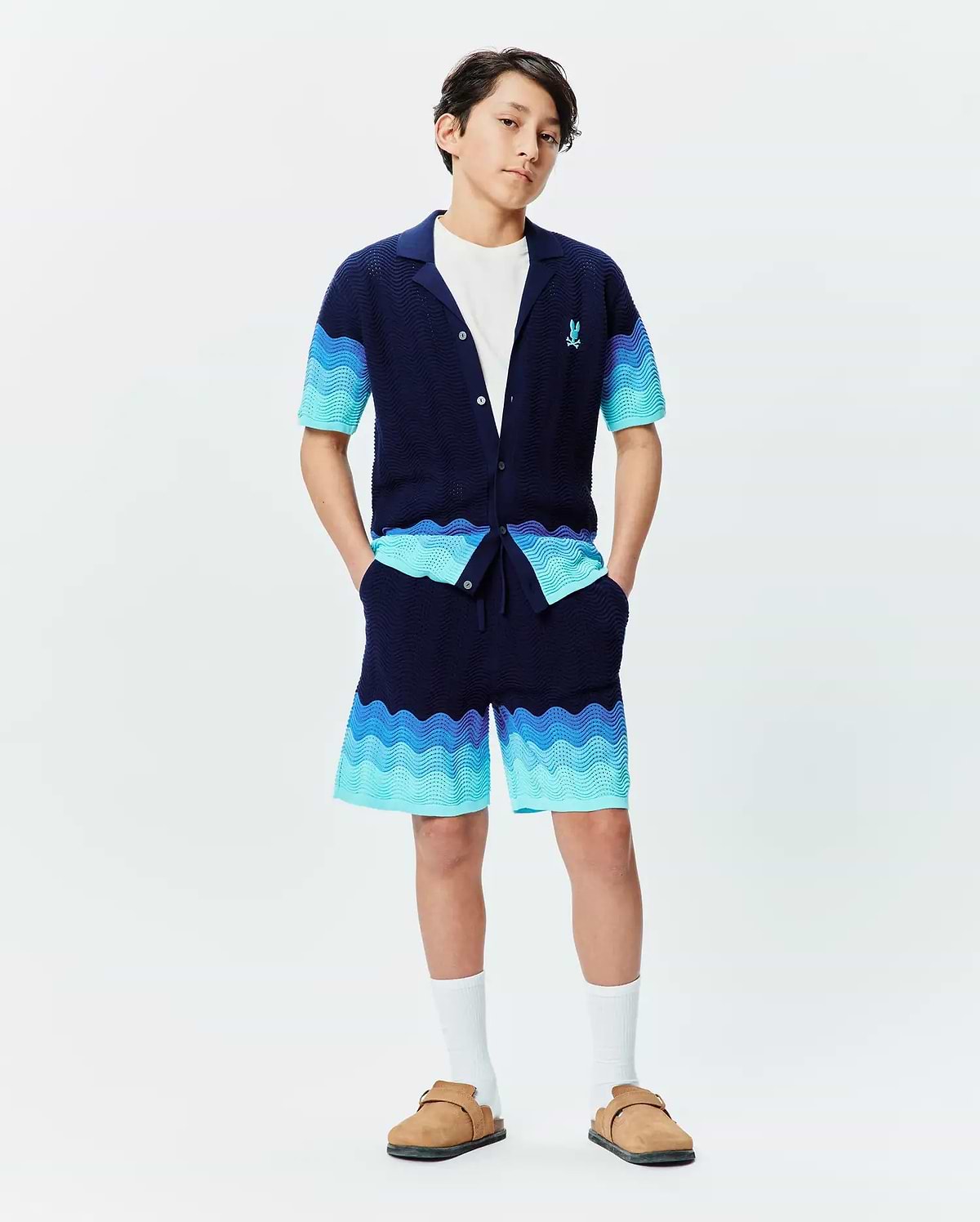 Psycho Bunny navy knit collared shirt and Kids Holden Knit Short set, featuring a wavy gradient pattern in blues and turquoise, textured knit fabric, and a small embroidered blue bunny skull logo on the left chest. (4)