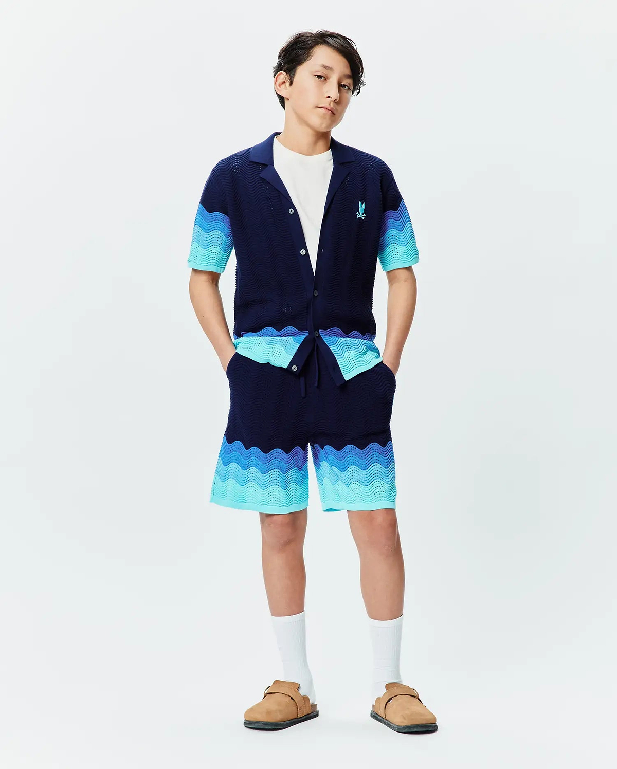 Psycho Bunny navy knit collared shirt and Kids Holden Knit Short set, featuring a wavy gradient pattern in blues and turquoise, textured knit fabric, and a small embroidered blue bunny skull logo on the left chest. (4)