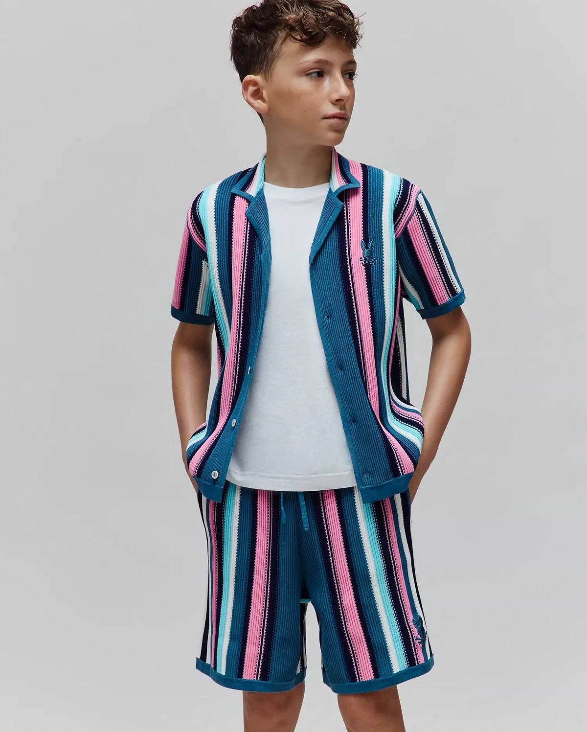 Kids Cliff Knit Shirt and matching shorts, featuring vibrant teal, pink, blue, white vertical stripes. Classic fit textured knit with small embroidered Psycho Bunny skull logo on chest and shorts.