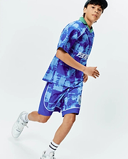 Vibrant blue and light blue distressed pattern jersey top with green collar, white Psycho Bunny chest text, and matching KIDS MICAH SOCCER SHORT with white piping and green bunny skull leg logo.
