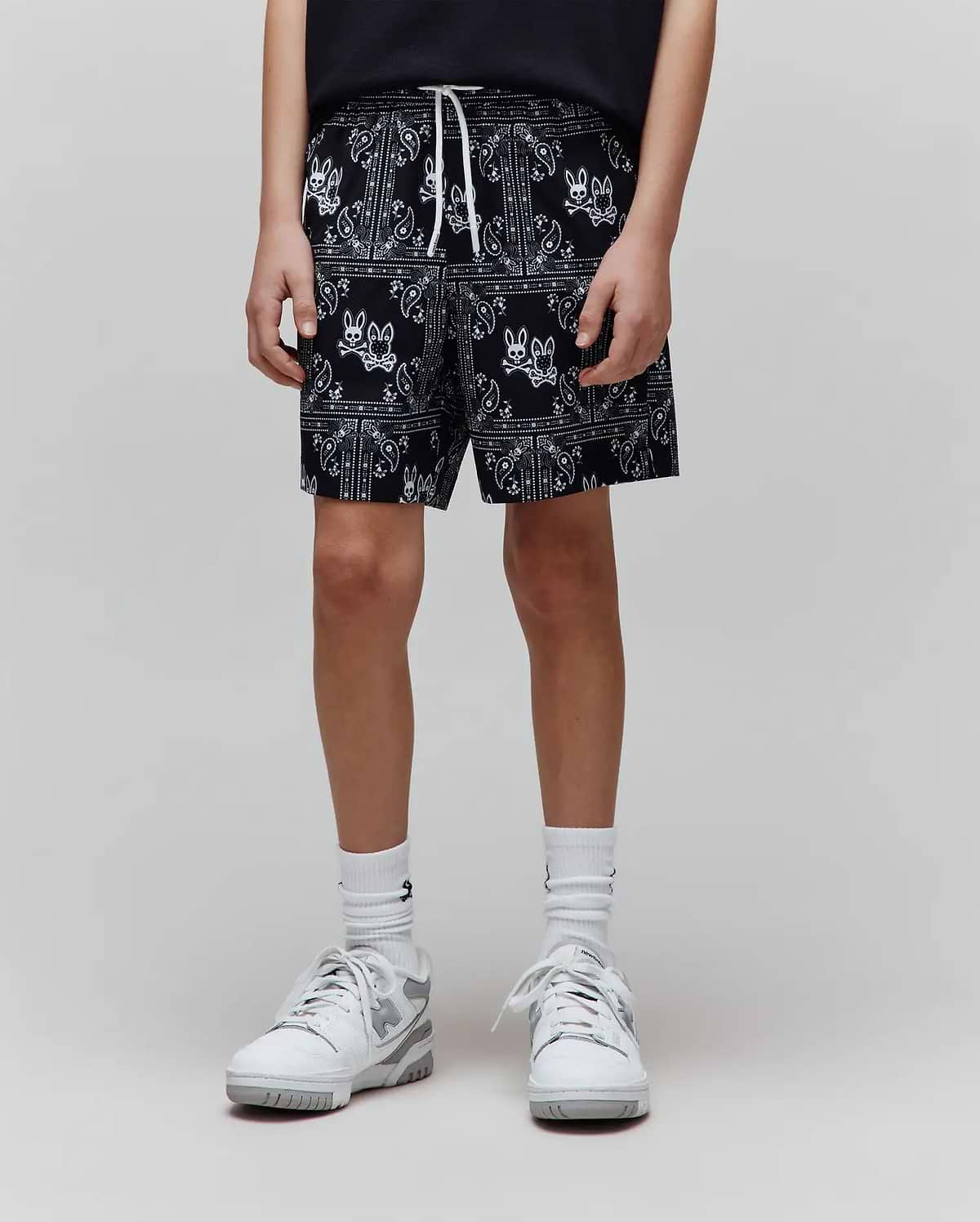 Kids Luke Swim Trunk in black with an all-over white bandana print featuring the Psycho Bunny skull logo, relaxed fit, and white drawstring.