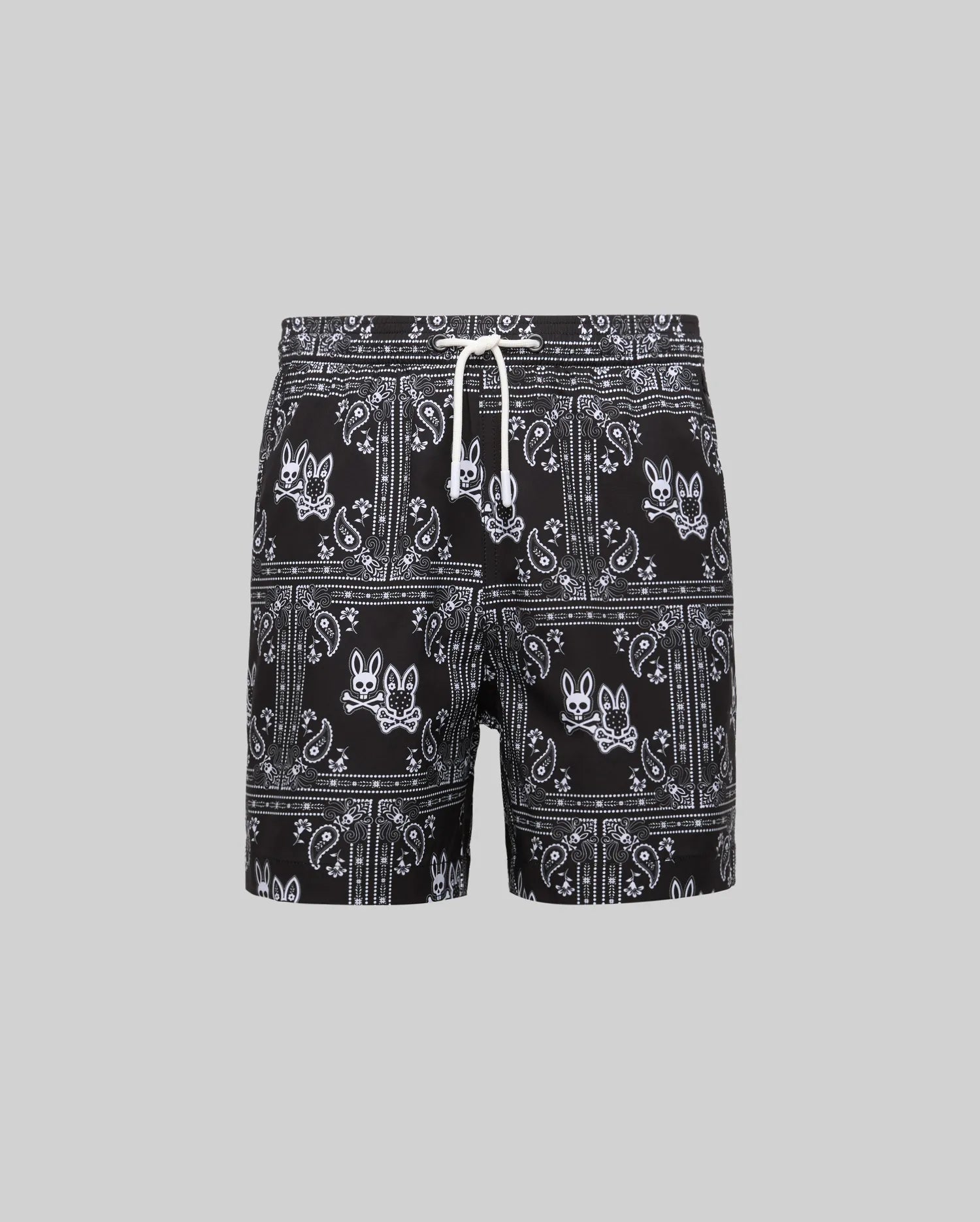 Kids Luke Swim Trunk in black with an all-over white bandana paisley pattern featuring repeated Psycho Bunny skull logos and a white drawstring.