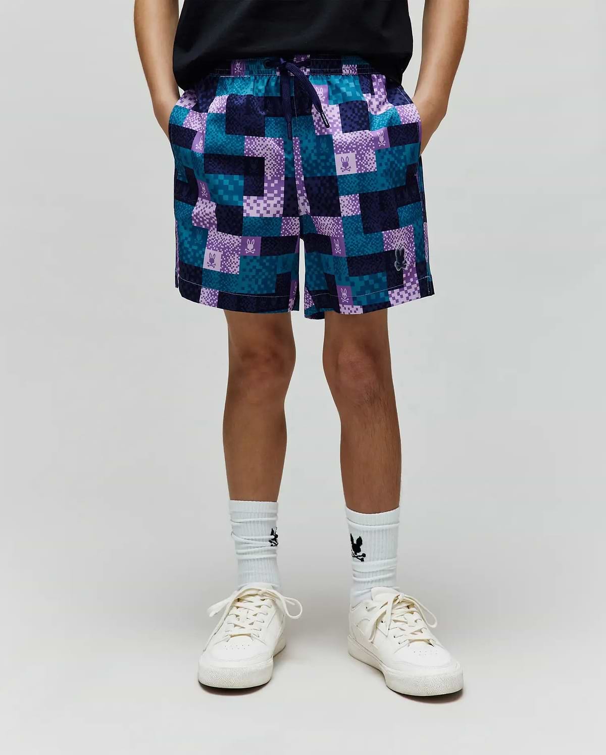Kids Olivier All Over Bunny Swim Trunk in a relaxed fit, featuring a vibrant teal, purple, and navy patchwork pattern with small integrated Psycho Bunny skull logos throughout. Smooth, quick-dry fabric.