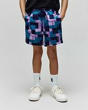 Kids Olivier All Over Bunny Swim Trunk in a relaxed fit, featuring a vibrant teal, purple, and navy patchwork pattern with small integrated Psycho Bunny skull logos throughout. Smooth, quick-dry fabric.
