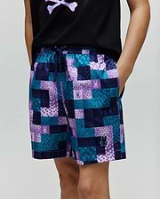 Kids Olivier All Over Bunny Swim Trunk with a vibrant pixelated teal, dark blue, and purple checkered pattern, featuring small bunny skull logos and a rubberized Psycho Bunny logo on the lower left leg.