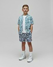 Kids Josh Swim Trunk and matching short-sleeve button-up shirt in a white and teal pixelated pattern featuring the Psycho Bunny skull logo, with a small red logo on the trunk, all in a relaxed fit. (4)