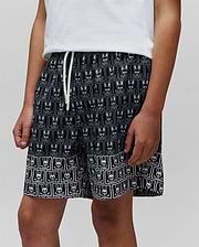 Kids Keon Swim Trunk, black with white all-over Psycho Bunny skull and crossbones grid print, relaxed fit, smooth quick-dry fabric, and white drawstring. (2)