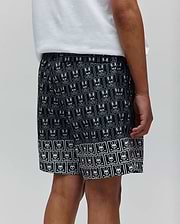 Kids Keon Swim Trunk featuring a relaxed fit, black fabric with an all-over white Psycho Bunny skull and crossbones logo pattern, and a distinct border design at the hem. (3)