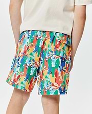 Kids Tanner Swim Trunk in vibrant multi-color, featuring an all-over abstract print of Psycho Bunny skull logos and bunny silhouettes, with a relaxed fit and a cargo pocket.