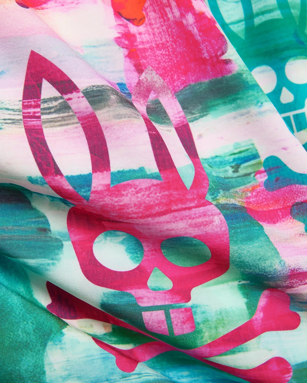 Kids Nate All Over Print Swim Trunk with a vibrant abstract watercolor pattern in hot pink, teal, and green, featuring large repeating Psycho Bunny skull and crossbones logos on smooth fabric.