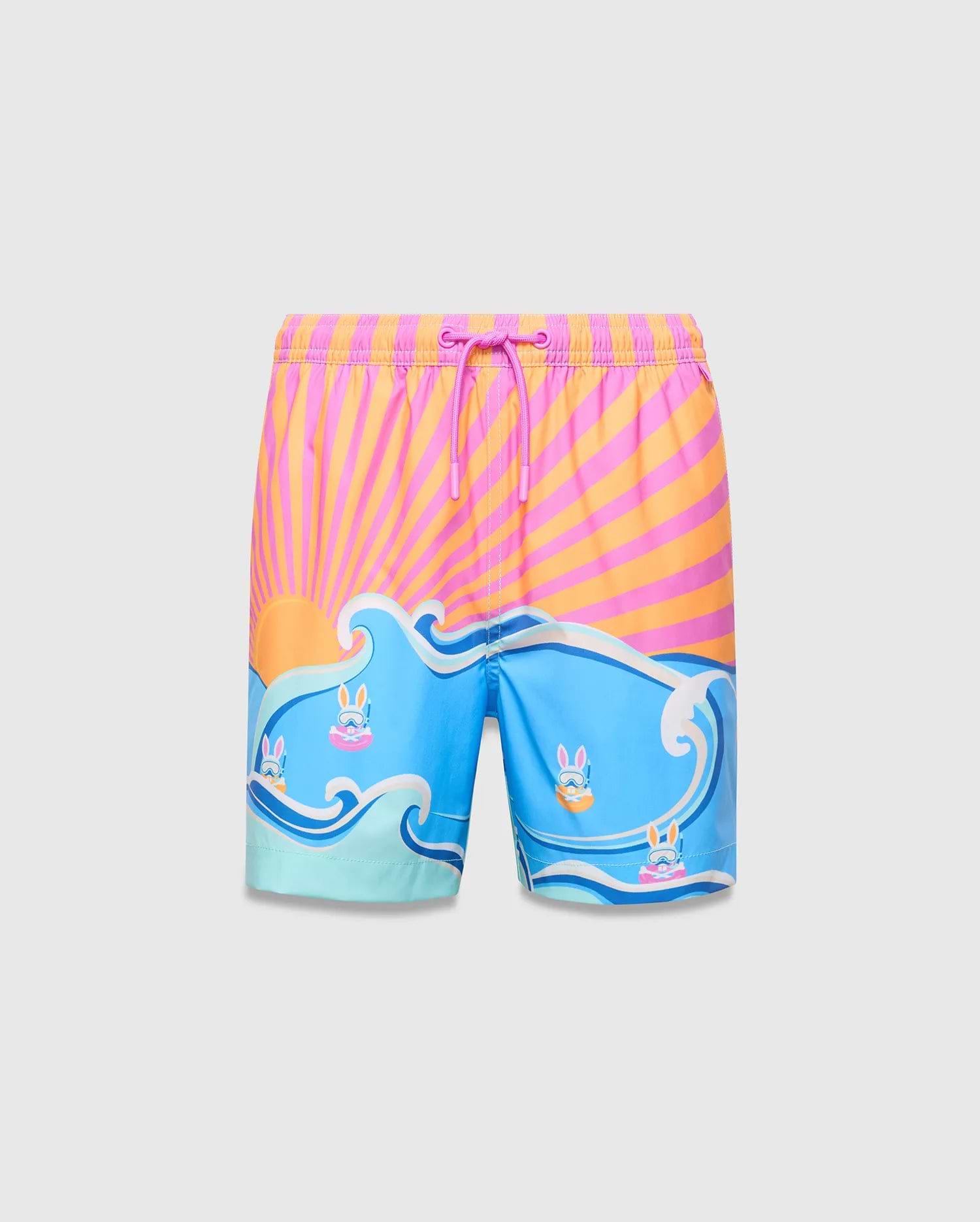 Kids Ray Swim Trunk 6 with a vibrant pink and orange sunburst top, flowing into blue waves featuring small Psycho Bunny skull logos wearing goggles, relaxed fit.