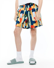 Kids Wes All Over Print Swim Trunk, a relaxed fit, quick-dry swim trunk with a vibrant multi-color abstract pattern in navy, orange, yellow, red, and teal, featuring small repeated Psycho Bunny skull logos.