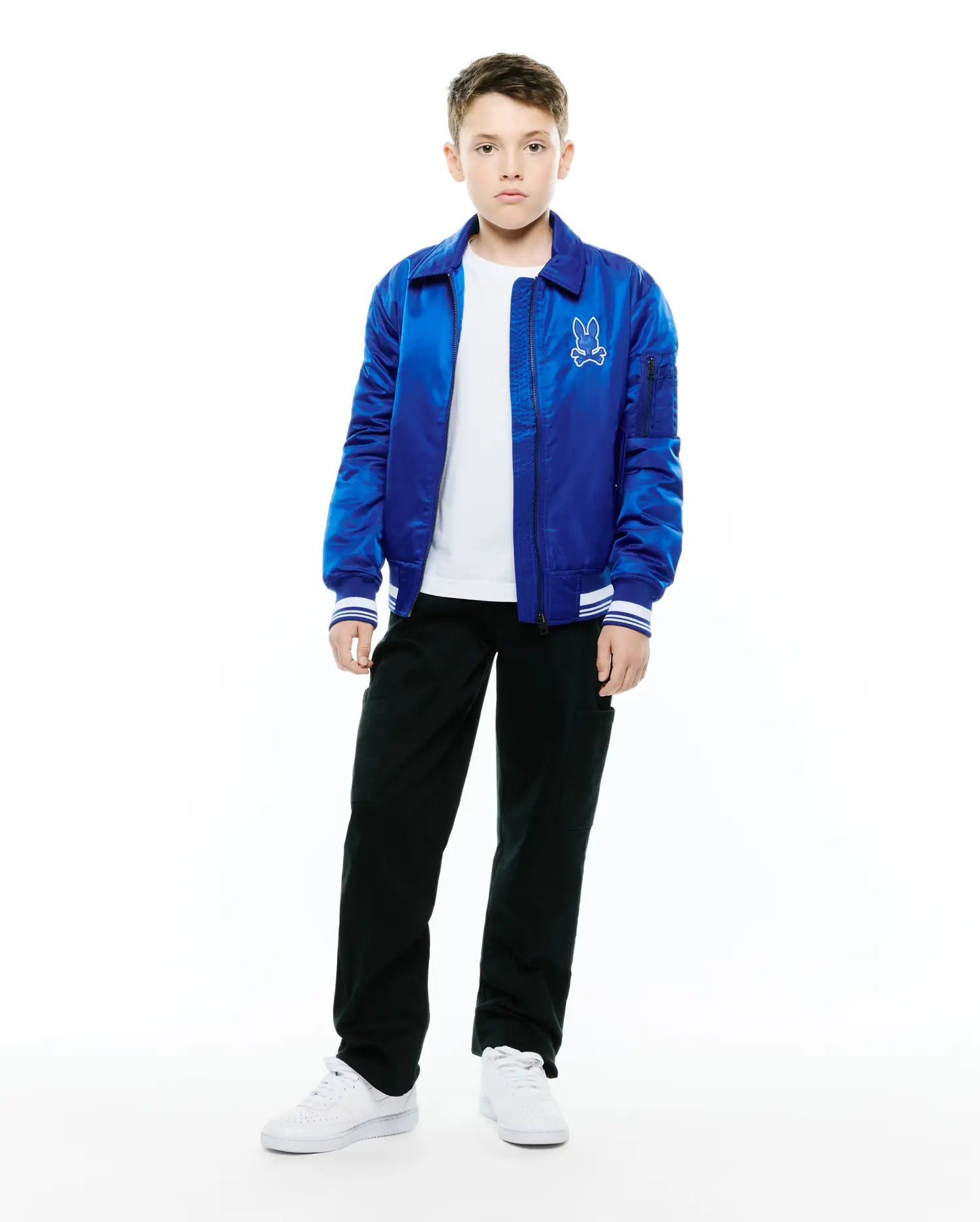 Kids Nathaniel Satin Coach Jacket, royal blue, shiny satin, full-zip, classic collar, ribbed cuffs with white stripes, utility sleeve pocket, embroidered white Psycho Bunny skull logo left chest.