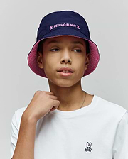 Kids Luke Reversible Bucket Hat in navy with pink Psycho Bunny embroidery and a white jersey t-shirt with a small embroidered Psycho Bunny skull logo on the left chest.