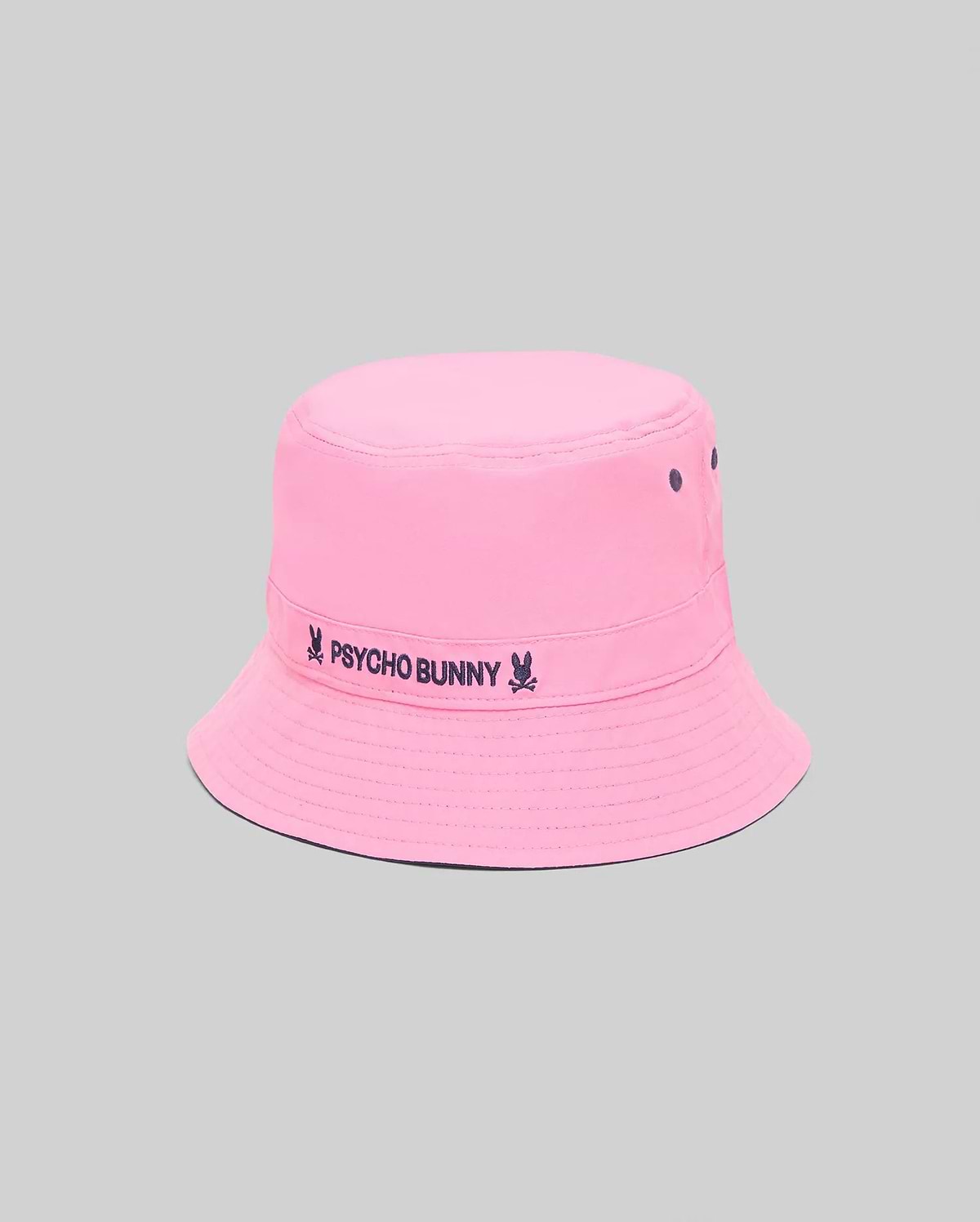 Kids Luke Reversible Bucket Hat in bright pink, featuring a dark blue embroidered Psycho Bunny skull and text logo on the band, with matching dark blue ventilation eyelets.