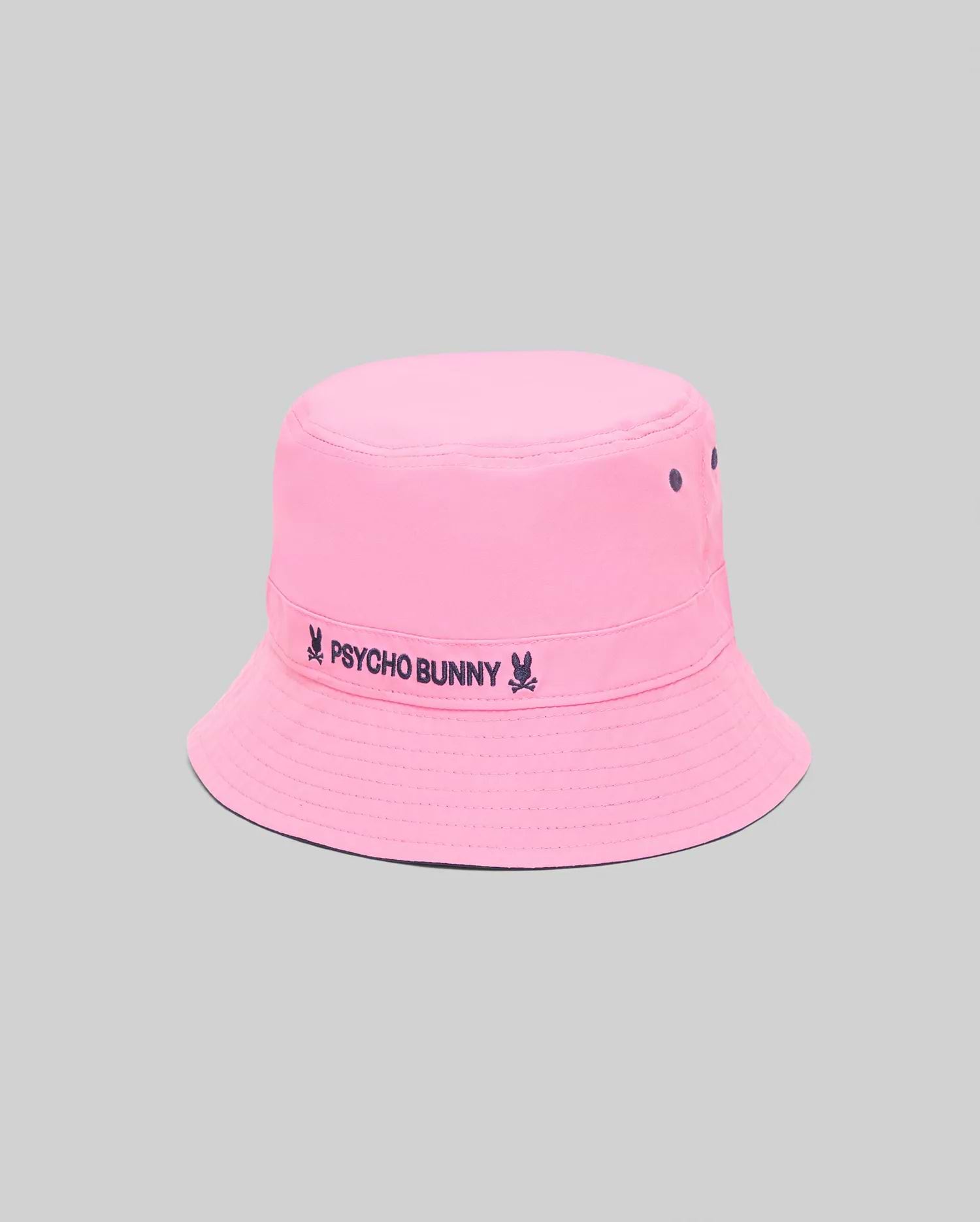 Kids Luke Reversible Bucket Hat in bright pink, featuring a dark blue embroidered Psycho Bunny skull and text logo on the band, with matching dark blue ventilation eyelets.