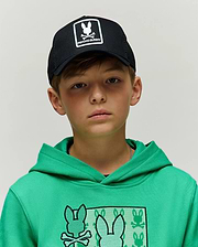 Kids Adamo Trucker Cap, black with white Psycho Bunny logo patch, paired with a bright green jersey knit hoodie featuring a large chest graphic of multiple Psycho Bunny skull logos.