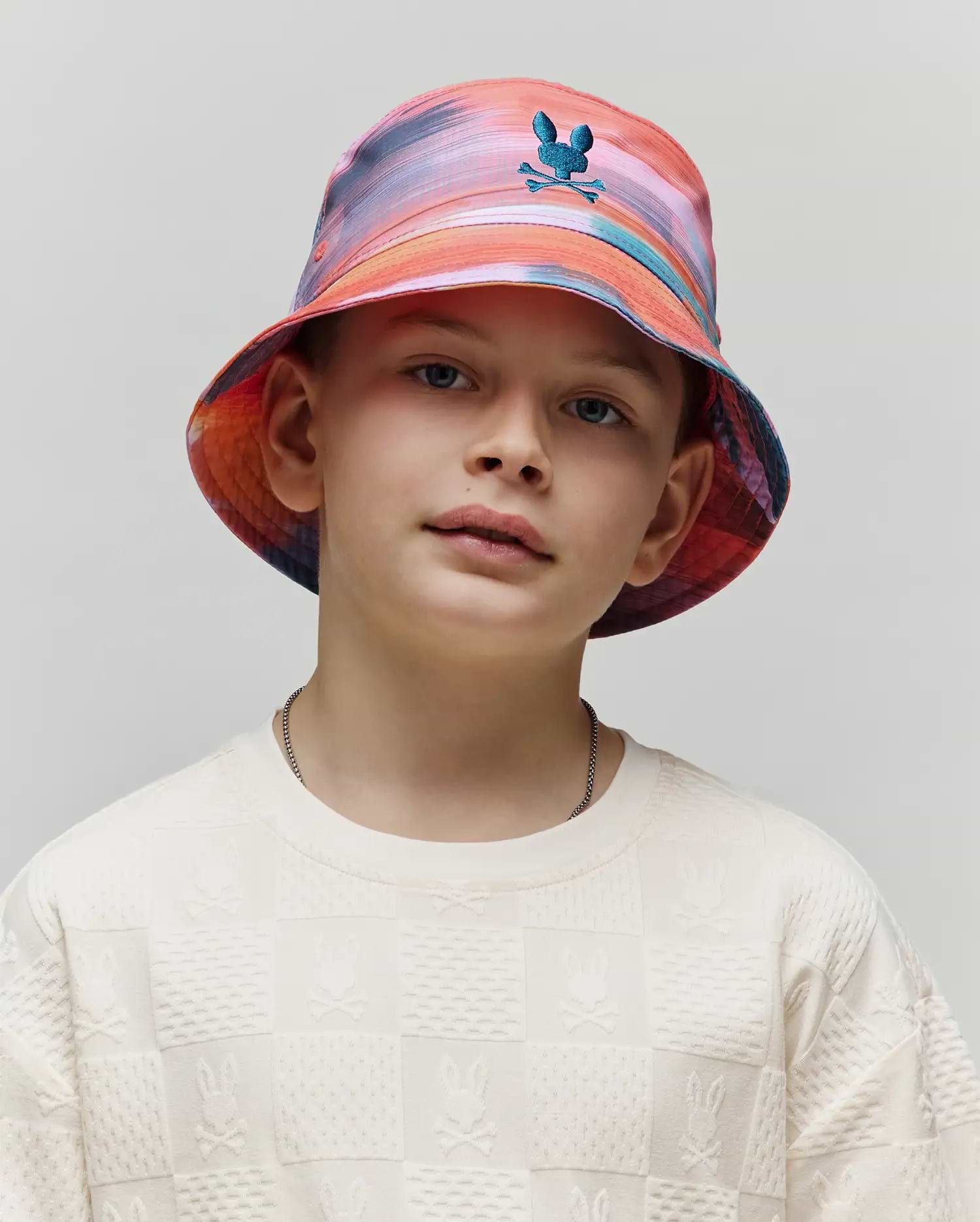 Kids Raphael Bucket Hat in vibrant multi-color tie-dye with a small teal embroidered Psycho Bunny logo, paired with an off-white textured long-sleeve crewneck featuring an all-over embossed checkerboard Psycho Bunny pattern.