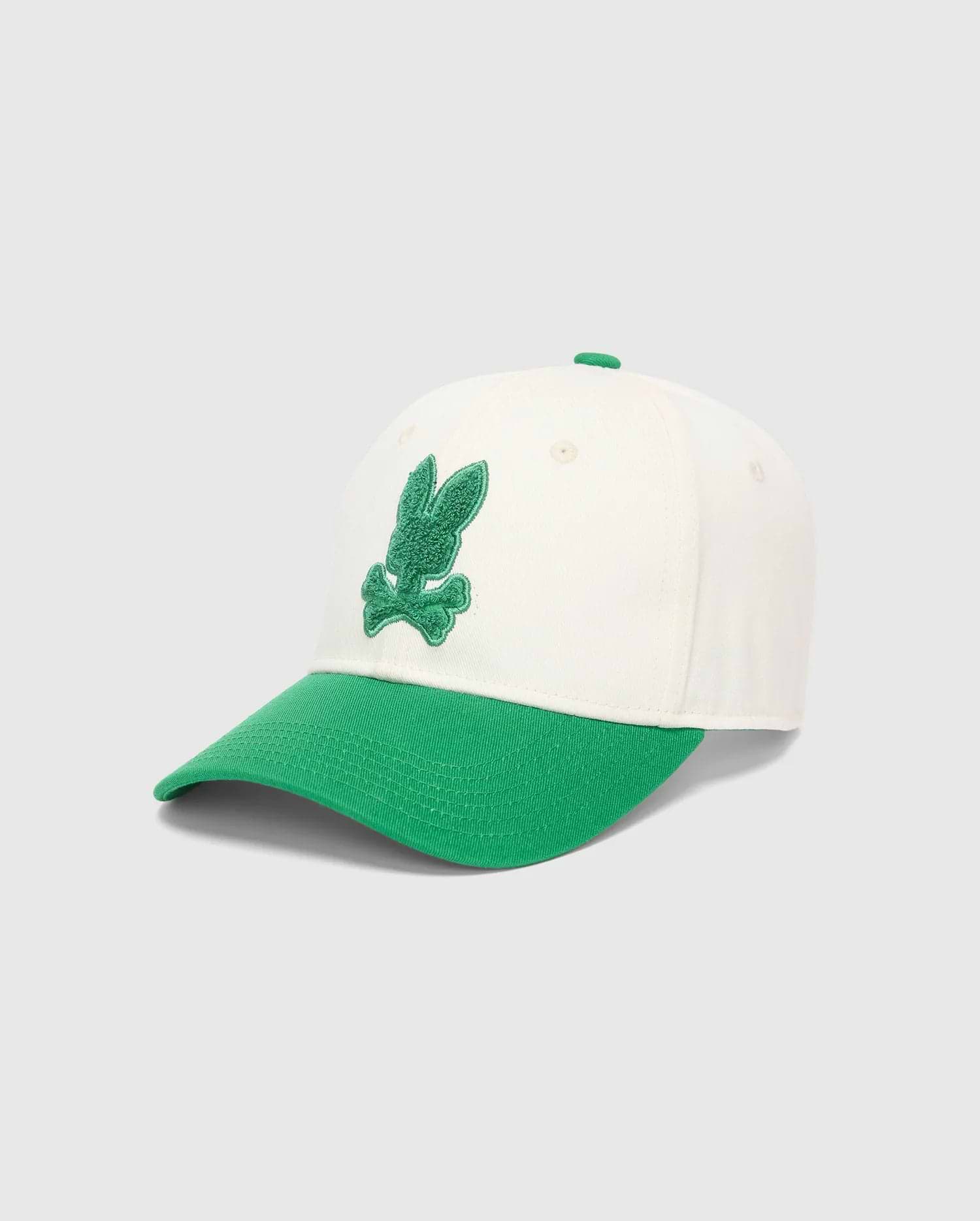 Kids Craig Baseball Cap, cream cotton twill crown with a vibrant green brim and top button, featuring a prominent, textured green embroidered Psycho Bunny skull logo on the front.