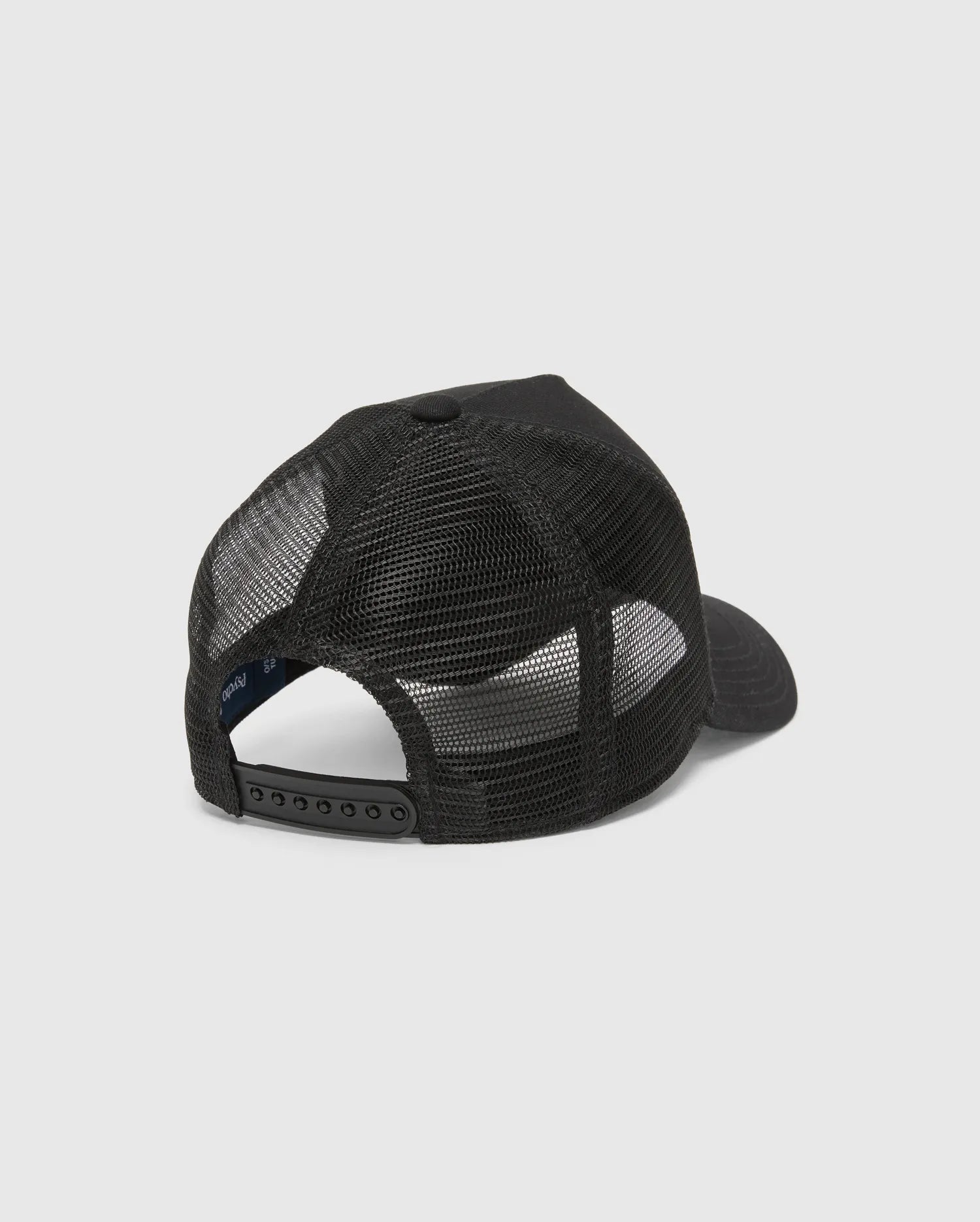 Black Kids Isaac Trucker Cap featuring a breathable mesh back, solid front panel, adjustable snapback closure, and a small inner Psycho Bunny brand tag.