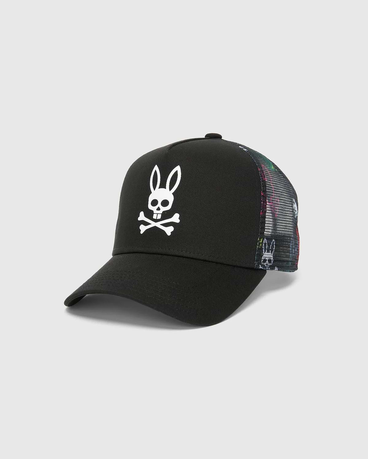 Kids Quintin Trucker Cap in black twill with a large white Psycho Bunny skull logo on the front. Features multicolor patterned mesh side and back panels with subtle bunny graphics.