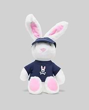 The PSYCHO BUNNY PLUSH - KO1700001 by Psycho Bunny is an ultra-soft bunny with pink ears and feet, a blue cap, and a bunny-and-crossbones shirt, giving it an edgy vibe against a plain gray background.