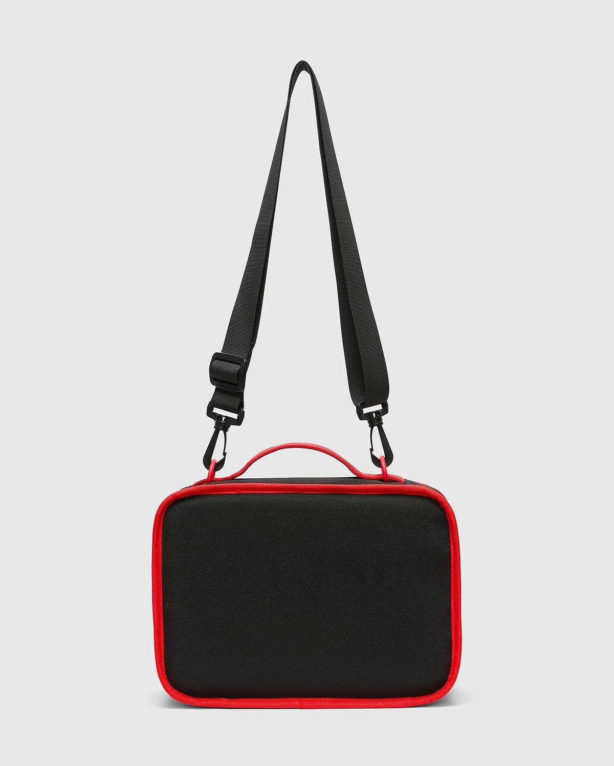 Kids Pal Lunch Box, sleek black durable fabric with vibrant red piping, a sturdy top handle, and an adjustable black shoulder strap featuring red carabiner clips.