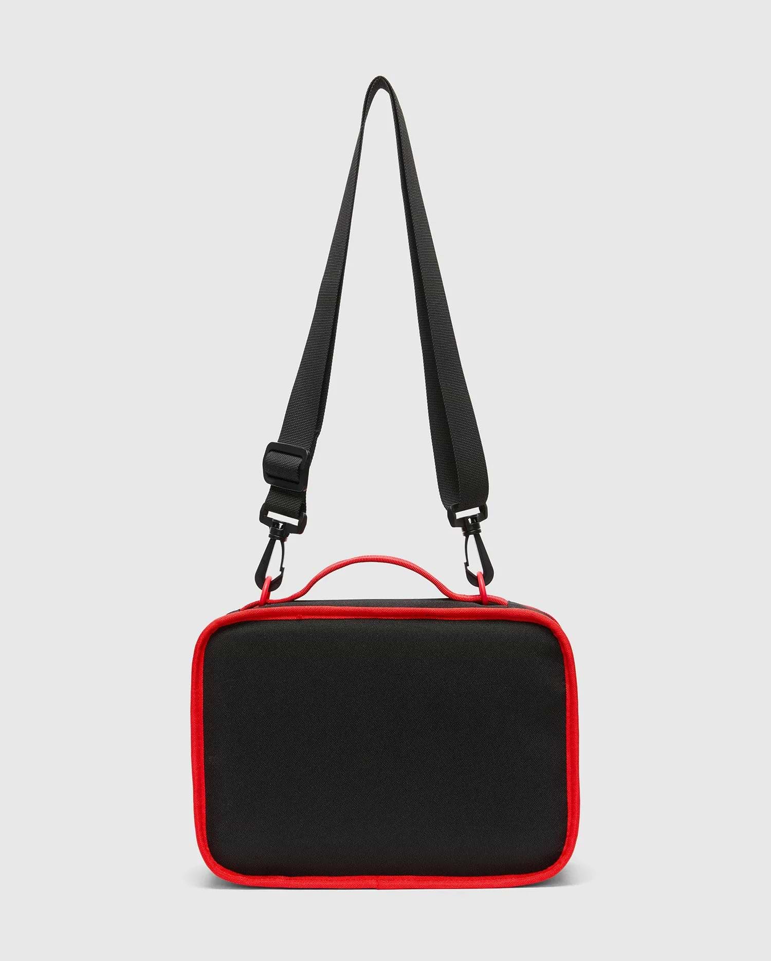 Kids Pal Lunch Box, sleek black durable fabric with vibrant red piping, a sturdy top handle, and an adjustable black shoulder strap featuring red carabiner clips.