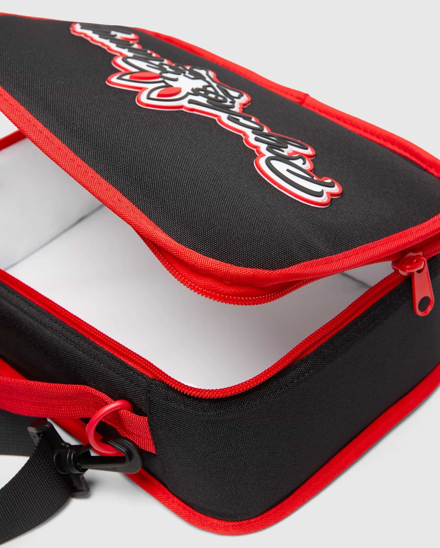Black Kids Pal Lunch Box with red piping and zipper, featuring a large 3D white and red Psycho Bunny logo on the top, and an adjustable black strap.