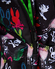 Kids Quintin Backpack in black durable woven fabric, featuring an all-over vibrant graffiti print with Psycho Bunny skull logos, outline bunnies, paint splatters, and crossbones, accented by a bright neon green zipper lining.